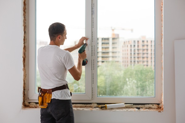 technician installing white plastic window frame